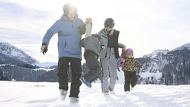 Gäste des Familienhotels Das Bayrischzell in Bayern sind mit ihren Kinder am Sudelfeld Skifahren.