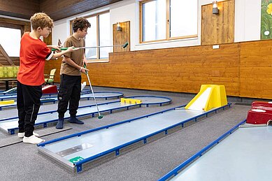 Zwei Kinder spielen Indoor Minigolf im Familienhotel Feldberger Hof