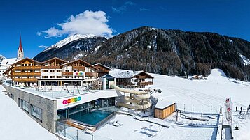 Das Familienhotel Huber in Südtirol umgeben von einer winterlichen Berglandschaft und großzügigen Außenanlage mit viel Platz zum Spielen für Kinder.