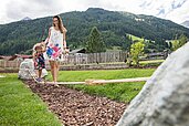 Eine Mutter hält ihre Tochter, die auf einem Seil balanciert auf dem Spielplatz am Alpenhotel Kindl in Tirol