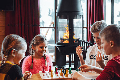 Kinder spielen Gesellschaftsspiele im Mons Silva Private Luxury Chalet in Südtirol.