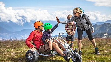 Vater und Sohn fahren Mountainkarts am Hochzeigerhaus in Tirol.