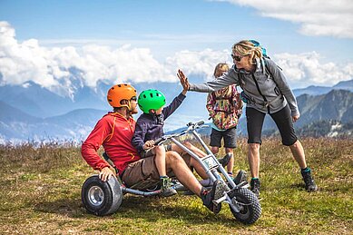 Vater und Sohn fahren Mountainkarts am Hochzeigerhaus in Tirol.