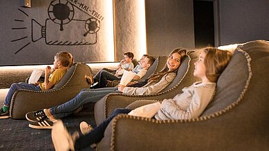 Kinder und Teens schauen im hoteleigenen Kino des Allgäuer Berghofs einen Film.