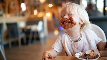 Lachender Junge beim Schokoeisessen im Restaurant des Familienhotels im Bayerischen Wald