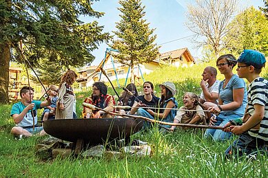 Stockbrot in einer Lagerfeuerrunde mit Kindern und Eltern im Familienhotel Mein Krug im Fichtelgebirge.