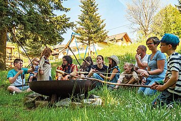 Stockbrot in einer Lagerfeuerrunde mit Kindern und Eltern im Familienhotel Mein Krug im Fichtelgebirge.