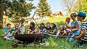 Stockbrot in einer Lagerfeuerrunde mit Kindern und Eltern im Familienhotel Mein Krug im Fichtelgebirge.