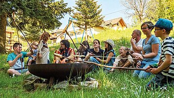 Stockbrot in einer Lagerfeuerrunde mit Kindern und Eltern im Familienhotel Mein Krug im Fichtelgebirge.