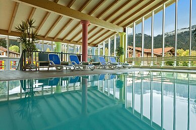 Schwimmbad mit Liegen und Panoramafenstern im Familienhotel Spa- & Familien-Resort Krone im Allgäu.