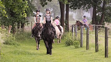 Kinder bei Ausritt mit Ponys und Pferden inmitten herrlicher Natur