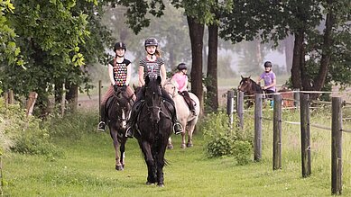 Kinder bei Ausritt mit Ponys und Pferden inmitten herrlicher Natur