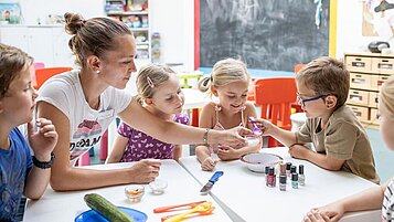 Lachende Kinder gemeinsam mit einer Betreuerin in der Kinderbetreuung im Familienhotel Kaiserhof in Tirol.