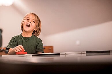 Mutter und Sohn spielen Airhockey im Spielbereich des Familienhotels Alpenhof Dolomit Family