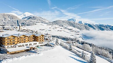 Luftaufnahme des Familienhotels Family Home Alpenhof im Winter.