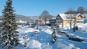 Das Familienhotel Mein Krug im Fichtelgebirge, umgeben von einer winterlichen, verschneiten Umgebung.