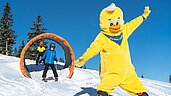 Kinder fahren auf Skiern durch einen Tunnel im Winter-Familienurlaub in Kärnten 