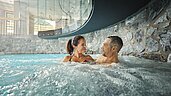 Eltern entspannen im Whirlpool des Familienhotels Alpenhotel Kindl in Tirol.