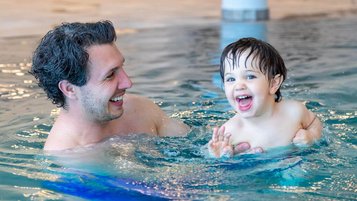 Vater und Kind haben Spaß im beheizten Indoor-Pool des Familien Resort Petschnighof, einem Familienhotel in Kärnten