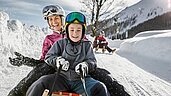 Kinder beim Rodeln am Familienhotel Kinderhotel Stefan in Tirol.