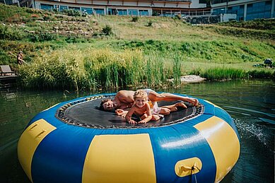 Vater und Kind auf dem Wassertrampolin im Familien Resort Petschnighof