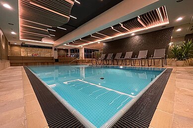 Das Indoor-Schwimmbad im Wellness- & Familienhotel Egger in Saalbach Hinterglemm ist gemütlich eingerichtet mit Pflanzen und Liegen zum Entspannen.