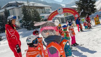 Viele Kinder stehen in Skiausrüstung im Rahmen der Kinder-Skischule von Michael Walchhofer nebeneinander.