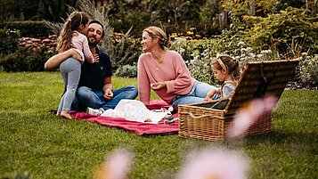 Familie beim Picknick in der Natur auf dem Außengelände des Familienhotels Landhaus Averbeck in der Lüneburger Heide.