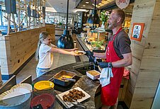 Kleines Mädchen wird am Buffet vom freundlichen Koch des Familienhotels Landhaus zur Ohe im Bayerischen Wald bedient.