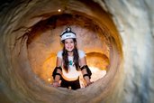 Höhlenabenteuer im Familienhotel Ungarn: Ein Mädchen erkundet strahlend den Klettertunnel im Kolping Family Resort – ein spannendes Erlebnis für kleine Entdecker.