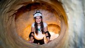 Höhlenabenteuer im Familienhotel Ungarn: Ein Mädchen erkundet strahlend den Klettertunnel im Kolping Family Resort – ein spannendes Erlebnis für kleine Entdecker.