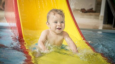 Baby auf der Babyrutsche im Kinderplanschbecken des Familienhotels Landgut Furtherwirt.