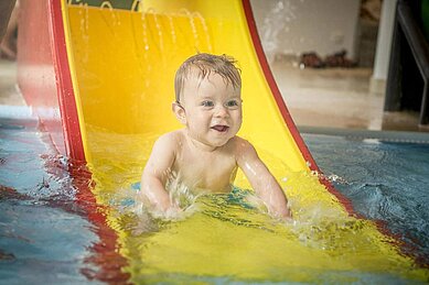 Baby auf der Babyrutsche im Kinderplanschbecken des Familienhotels Landgut Furtherwirt.