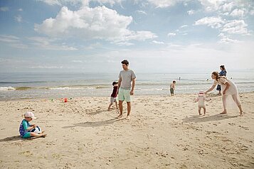 Eine Familie ist zu Gast im Familienhotel Seeklause an der Ostsee und bauen Sandburgen am Strand.