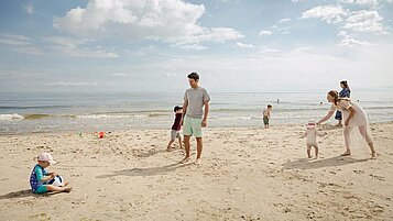 Eine Familie ist zu Gast im Familienhotel Seeklause an der Ostsee und bauen Sandburgen am Strand.