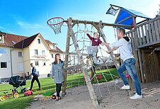 Familie mit spielt gemeinsam auf dem Außenspielplatz des Familienhotels Rhön Feeling.