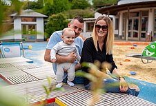 Papa spielt mit seinem Sohn im Sandkasten auf dem Außengelände des Familienhotels Kolping Hotel Spa & Family Resort in Ungarn.