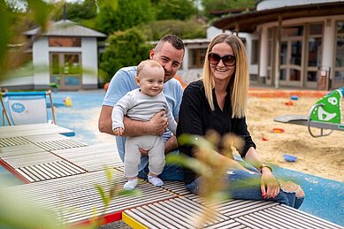 Papa spielt mit seinem Sohn im Sandkasten auf dem Außengelände des Familienhotels Kolping Hotel Spa & Family Resort in Ungarn.