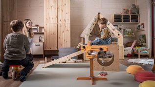 Kinder spielen im gemütlichen Indoor-Spielzimmer mit Holzhaus und Baukran im Familienhotel Elldus im Erzgebirge.