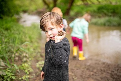 Kleiner Junge hat eine Matschkugel in der Hand und hat viel Spaß mit der Kinderbetreuung des Familienhotels Landhaus zur Ohre im Bayerischen Wald.