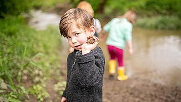 Kleiner Junge hat eine Matschkugel in der Hand und hat viel Spaß mit der Kinderbetreuung des Familienhotels Landhaus zur Ohre im Bayerischen Wald.