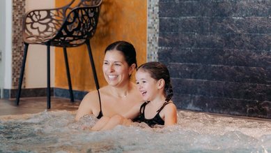 Mama und Kind entspannen gemeinsam im warmen Sprudelbecken im Familienhotel Amiamo im Salzburger Land.