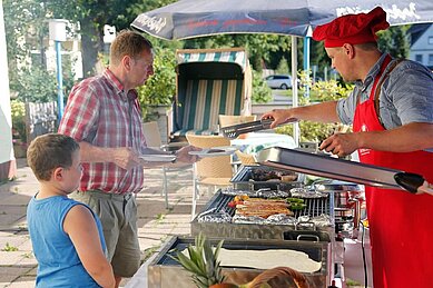 Ein Mann und ein Kind stehen am Grill und begutachten das Grill-Buffet im Familienhotel Mein Krug im Fichtelgebirge.