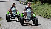 Zwei Kinder fahren ein Kartrennen auf dem Hof im Kinderhotel Bruckwirt in Oberösterreich.