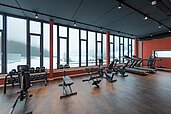 Modern ausgestatteter Fitnessraum mit Panoramafenstern bietet Ausblick auf die verschneite Winterlandschaft des Bayrischen Waldes im Familienhotel Schreinerhof.