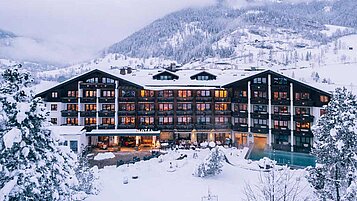 Das Familienhotel Kirchheimerhof in Kärnten, umgeben von einer großen Hotel-Außenanlage und winterlichen Berglandschaft.