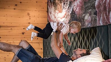 Vater bringt das Baby zu Bett im Familienhotel Galtenberg Family & Wellness Resort in Tirol.