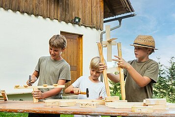 Drei Jungs bauen in der Bastelwerkstatt im Hotel Alpengasthof Hochegger etwas aus Holz