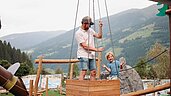 Vater und Sohn spielen auf dem Außenspielplatz vom Familotel Habachklause mit dem Seilzug