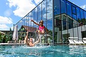 Familie planscht im großen Outdoor-Pool des Familienhotels Ulrichshof im Bayerischen Wald.